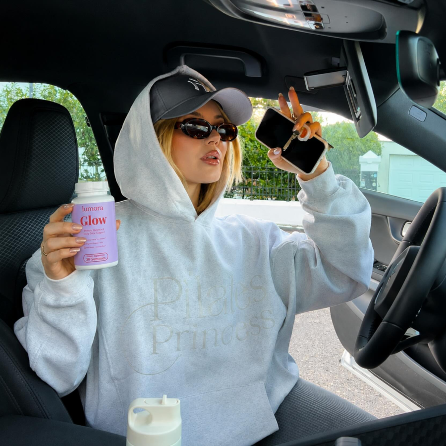 Woman holding Lumora Glow bottle in car